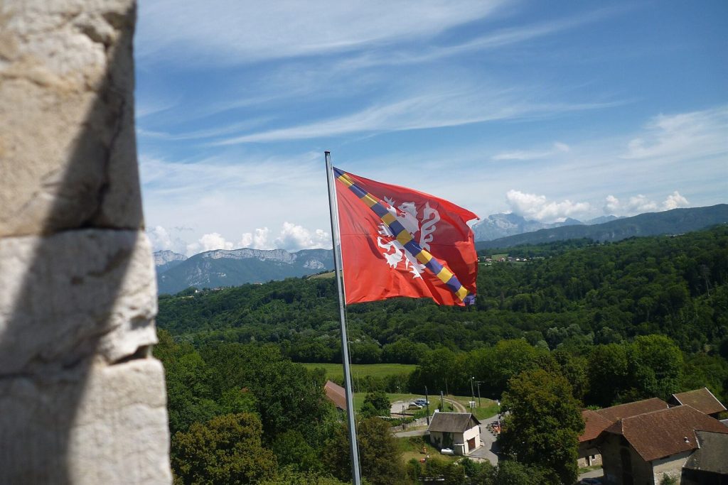 Drapeau aux armes des Menthon-Montrottier flottant sur le château, avec la vue sur la campagne et les montagnes