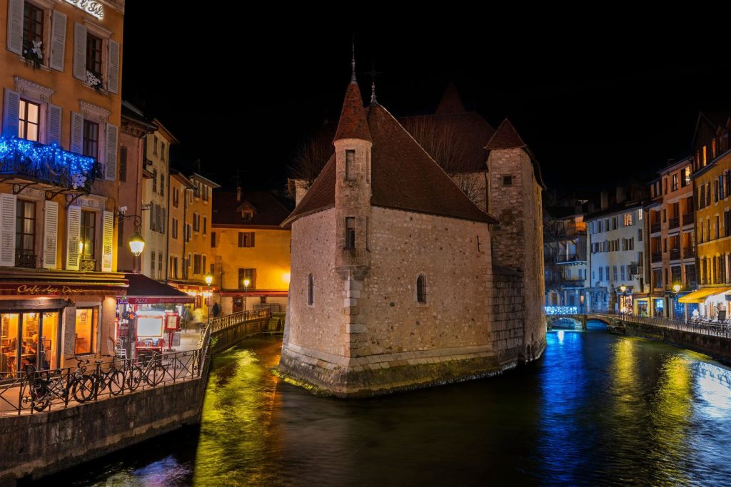 Le Palais de l'Isle éclairé la nuit au milieu du Thiou, à Annecy