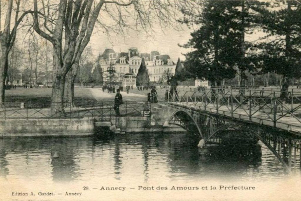 Carte postale ancienne : le pont des Amours avec une pile dans l'eau, et la préfecture au fond