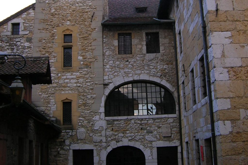 La cour intérieure du Palais de l'Isle à Annecy, avec sa tour et ses fenêtres à barreaux